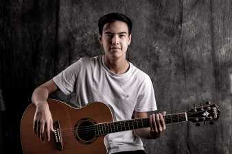 young man smiling and holding his guitar