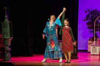 man and woman in costume on stage with their hands linked and raised in the air