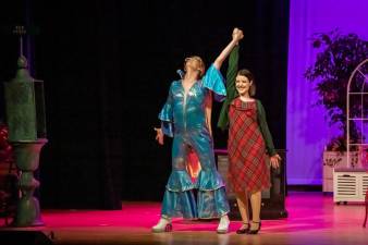 man and woman in costume on stage with their hands linked and raised in the air