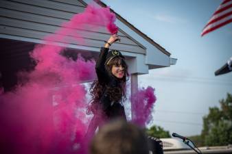 a woman smiling and holding a purple smoke grenade
