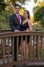 a young couple smiling on a bridge in their prom outfits
