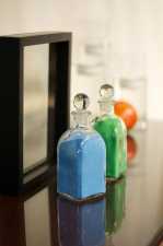 two bottles of colored sand on a table next to a glass frame