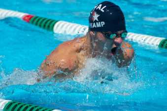 young man in a swimming cap taking a breath during his swimming race