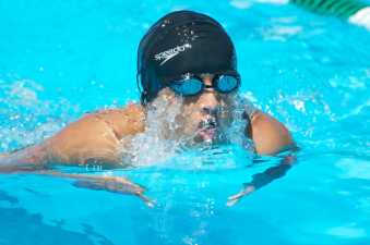 young man in a swimming cap taking a breath during his swimming race