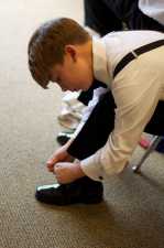 young boy tieing his dress shoes