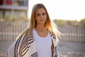 a young blond woman on a beach lokoing at the camera