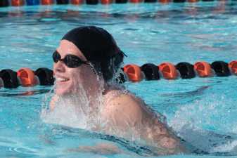 young man in a swimming cap taking a breath during his swimming race