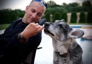 a man sitting on an outdoor chair feeding his dog