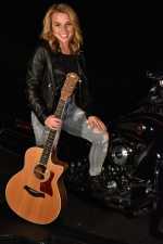 a young woman on a harley at night in her driveway, holding a guitar