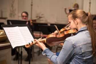 a young woman playing a violin while reading her sheet music