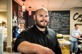 A male barista smiling in a coffee shop