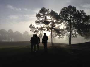 three golfers in the fog at dawn