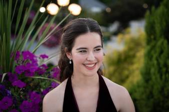 brunette girl wearing a black dress and looking to the side smiling