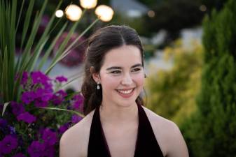 brunette girl wearing a black dress and looking to the side smiling