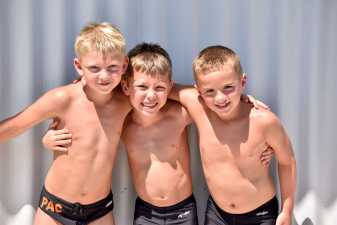 three young boys smiling for a photo at their swim meet