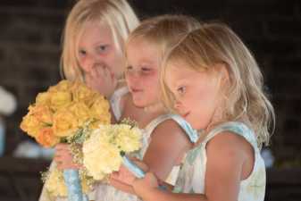 three young girls holding flowers at a wedding